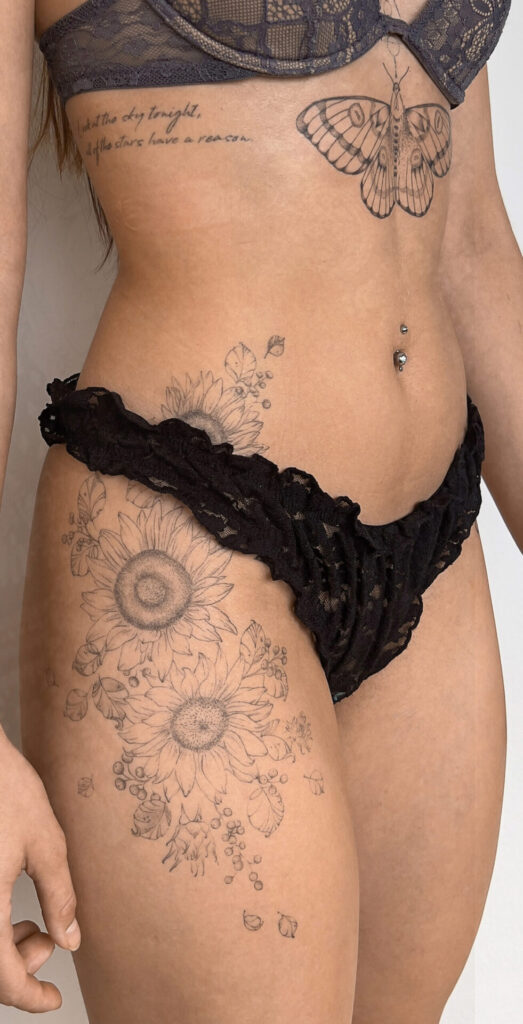 hip fineline flower tattoo with sunflowers and a butterfly from smasli ink an female tattoo artist working in salzburg austria