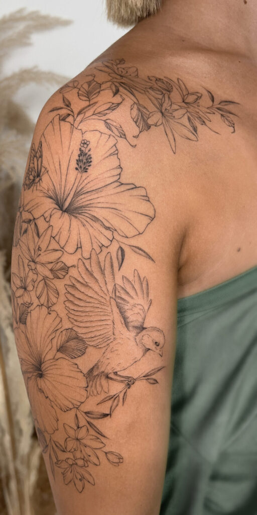 upper arm fineline flower tattoo with a lily and a bird from smasli ink an female tattoo artist working in salzburg austria