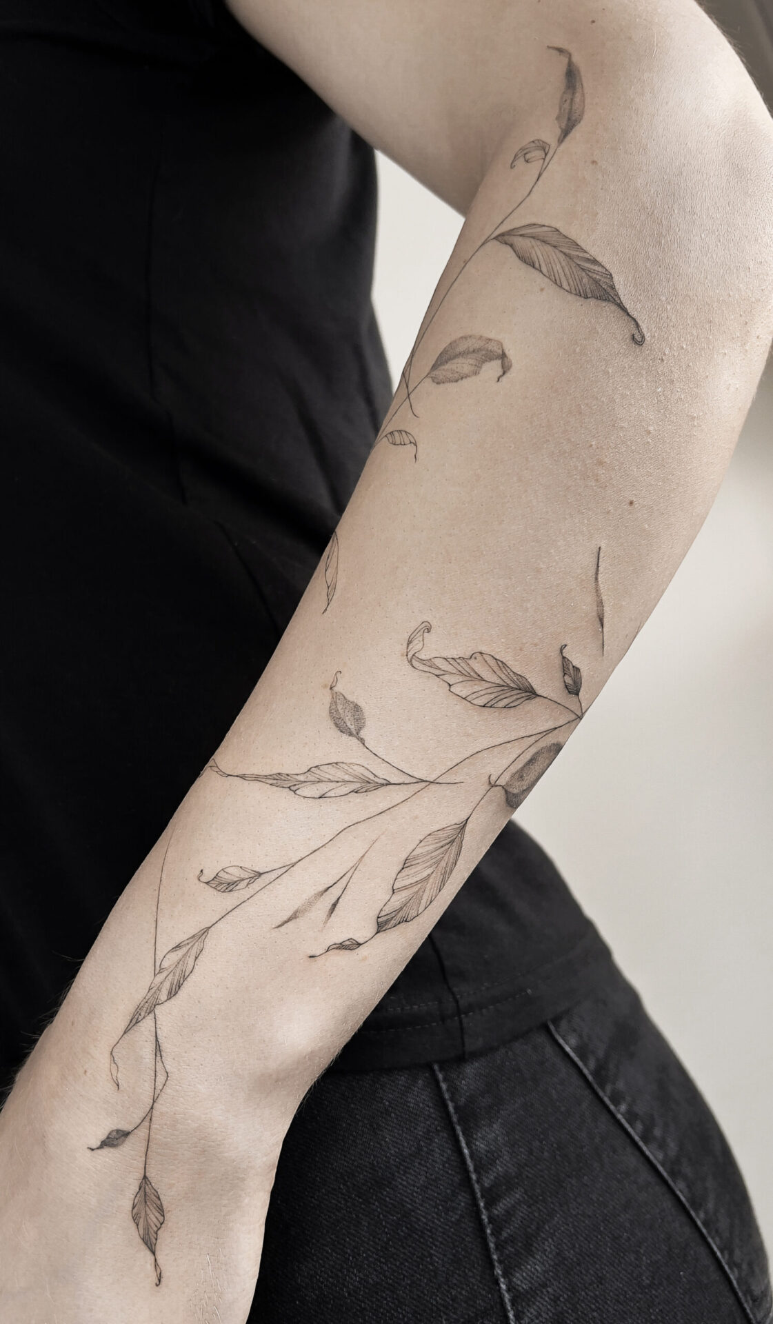forearm fineline flower tattoo with leaves from smasli ink an female tattoo artist working in salzburg austria