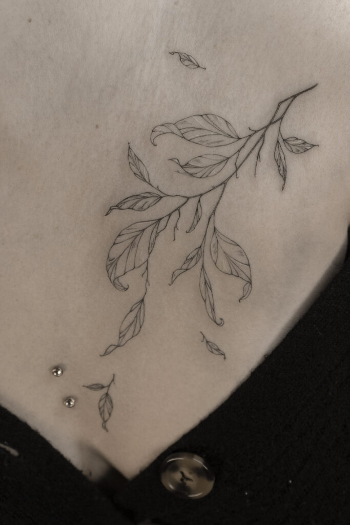 breast fineline flower tattoo with leaves from smasli ink an female tattoo artist working in salzburg austria