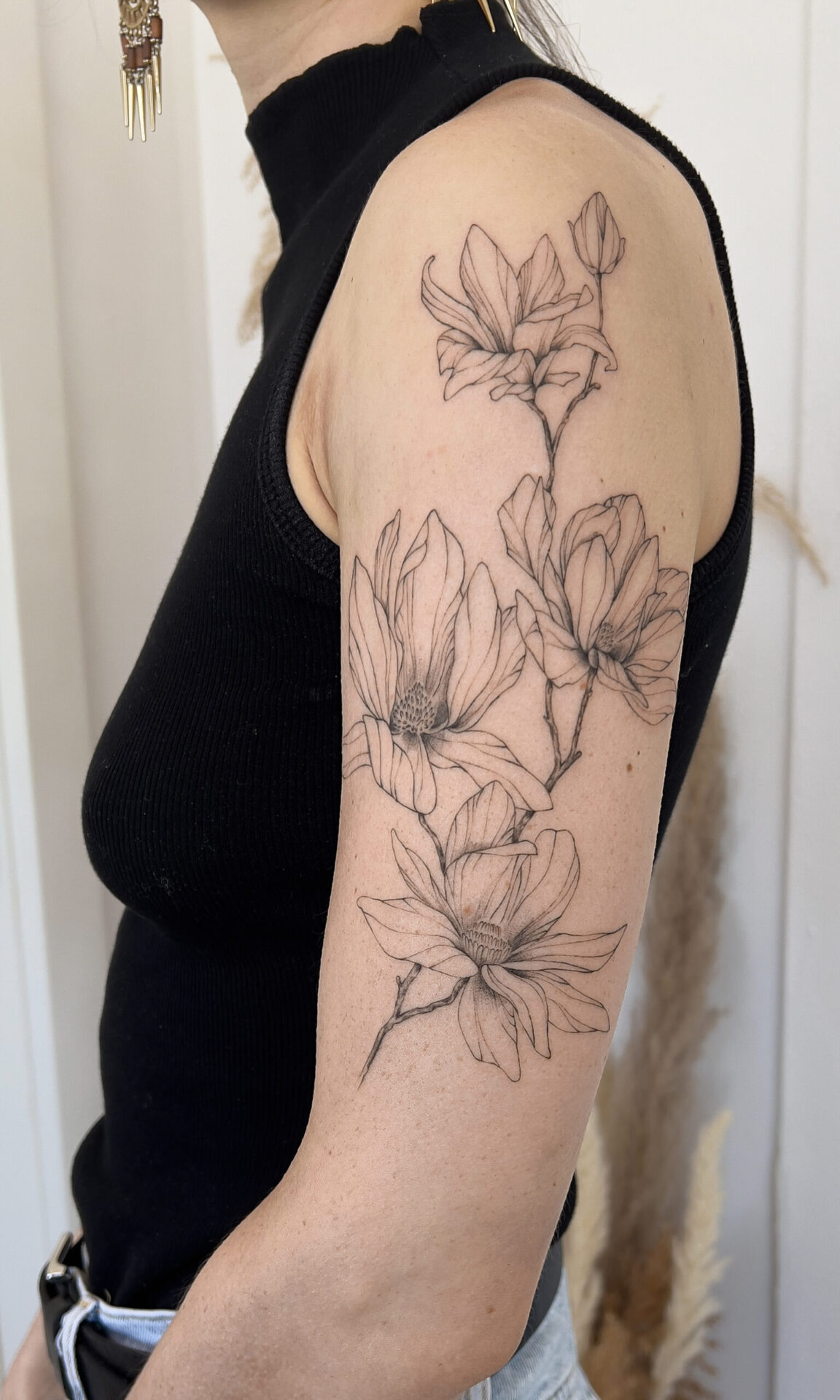 upper arm fineline flower tattoo with magnolia from smasli ink an female tattoo artist working in salzburg austria