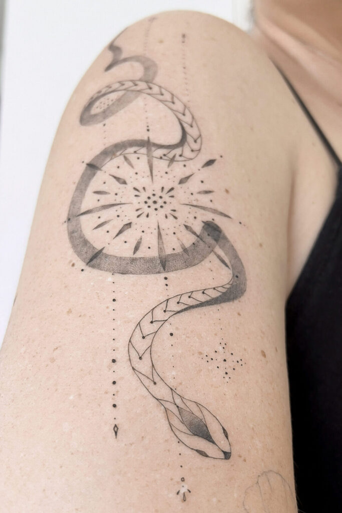 upper arm fineline snake tattoo with ornaments from smasli ink an female tattoo artist working in salzburg austria