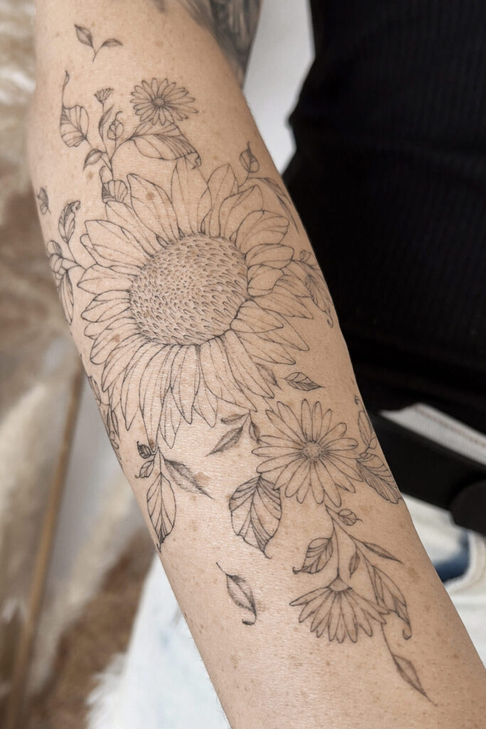 forearm fineline flower tattoo with a sunflower from smasli ink an female tattoo artist working in salzburg austria